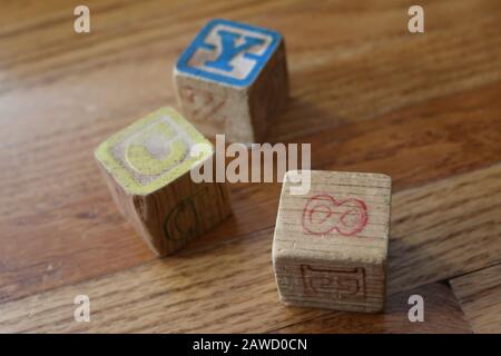 Tre vecchi Blocchi colorati in legno Alphabet numero su pavimento in legno di luce naturale Foto Stock