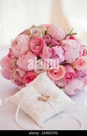 bellissimo bouquet di peonie e altri fiori rosa con anelli da sposa per sposi novelli Foto Stock