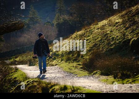 Un fotografo che cammina lungo un sentiero panoramico nel Lake District, vicino a Buttermere Foto Stock