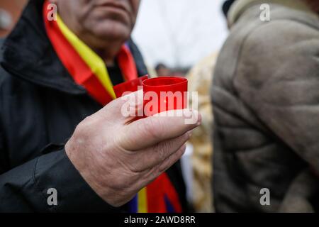 Profondità di campo poco profonda (fuoco selettivo) immagine con le mani di un uomo che tiene una candela all'aperto in una giornata fredda piovosa. Foto Stock