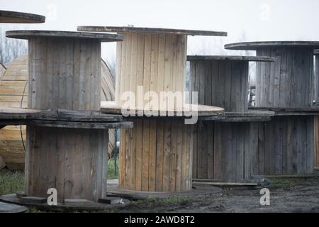 Avvolgicavo in legno vuoto all'aperto durante una fredda giornata di pioggia. Foto Stock