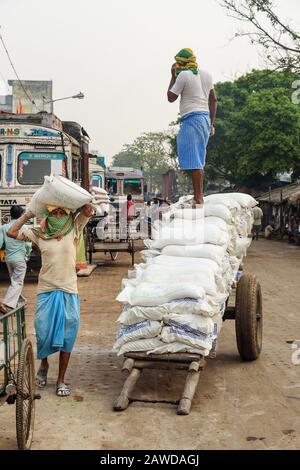 I lavoratori scaricano i bagagli da camion sulla strada a Kolkata. India Foto Stock