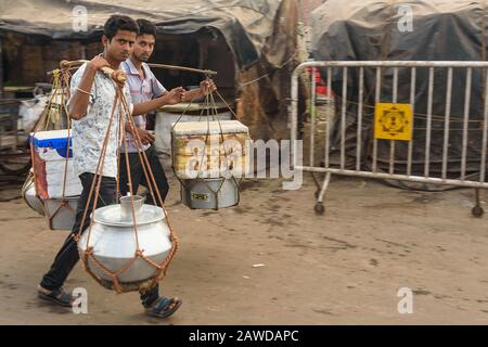 Gli uomini indiani portano cibo e bevande in pentole sul giogo lungo la strada. Calcutta. India Foto Stock
