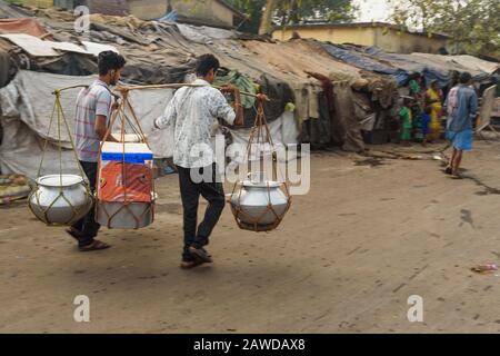 Gli uomini indiani portano cibo e bevande in pentole sul giogo lungo la strada. Calcutta. India Foto Stock