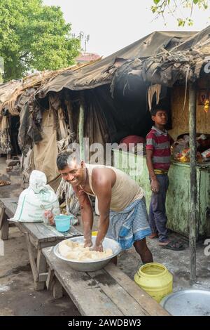Gli uomini indiani preparano l'impasto per i chapati sulla strada a Kolkata. India Foto Stock
