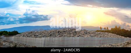 Montagna grande spazzatura pile e l'inquinamento circondato da recinzioni in ferro al sole è impostazione sullo sfondo, pile di stink e residui tossici, Questi wa Foto Stock