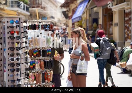 Atene, Grecia - 18 maggio 2019: I turisti camminano per le strade fiancheggiate da negozi di souvenir e caffè all'aperto lungo il marciapiede nella zona turistica di Plaka di Atene, Gr Foto Stock