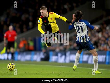 Gerard Deulofeu di Watford (a sinistra) prende un tumble dopo una sfida da Brighton e Hove Albion's Ezequiel Schelotto (a destra) durante la partita della Premier League all'AMEX Stadium, Brighton. Foto Stock