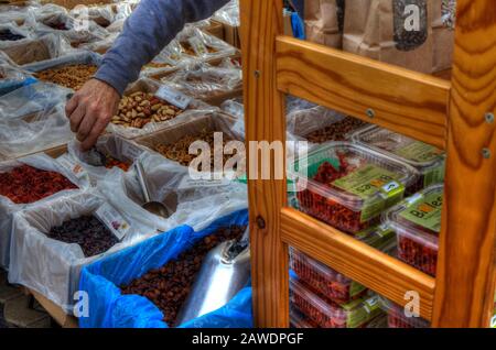 Primo piano della mano di un venditore che serve noci nel mercato Alameda Foto Stock