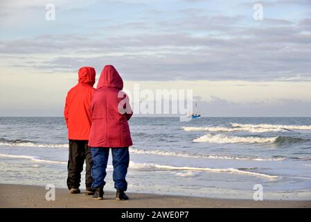 Due persone sulla spiaggia che guardano un granchio decespugliatore fuori Norderney, Mare del Nord, Isole Frisone Orientali, Bassa Sassonia, Germania Foto Stock