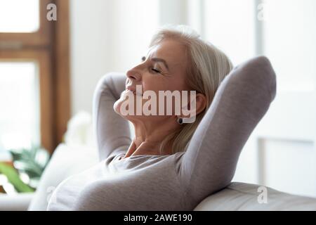 Calma donna matura rilassarsi sul divano con gli occhi chiusi Foto Stock