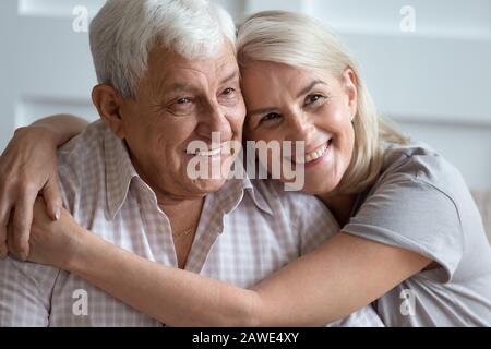 Ritratto headshot di coppia amorevole anziani abbracciando a casa Foto Stock