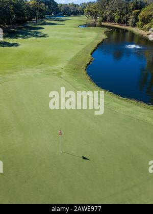 Bassa foto aerea di pin su un campo da golf con fairway sullo sfondo. Foto Stock