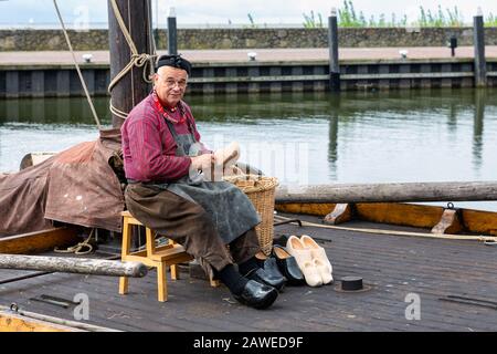 Pescatore in costume tradizionale che fa zoccoli presso la storica nave a vela Foto Stock