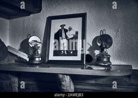 Una vecchia foto di famiglia dei custodi si trova in una cornice sul camino accanto alla lampada kerosene Foto Stock