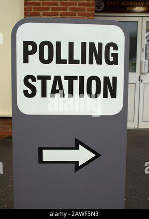 Grande stazione DI POLLING indipendente firmare in un parco giochi scuola umida, con un simbolo di freccia che punta alla zona di registrazione. Foto Stock