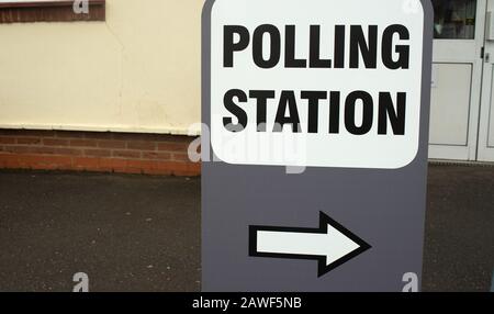 Grande stazione DI POLLING indipendente firmare in un parco giochi scuola umida, con un simbolo di freccia che punta alla zona di registrazione. Foto Stock