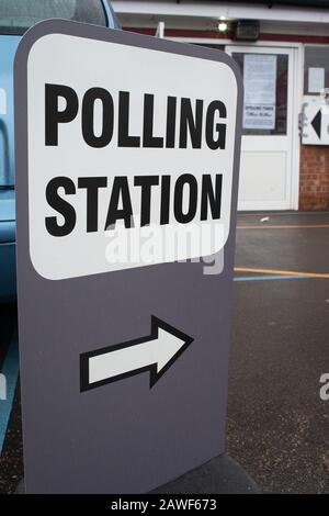 Grande stazione DI POLLING indipendente firmare in un parco giochi scuola umida, con un simbolo di freccia che punta alla zona di registrazione. Foto Stock