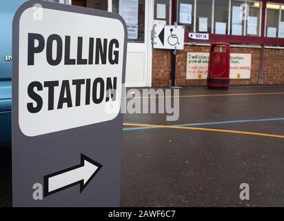 Grande stazione DI POLLING indipendente firmare in un parco giochi scuola umida, con un simbolo di freccia che punta alla zona di registrazione. Foto Stock