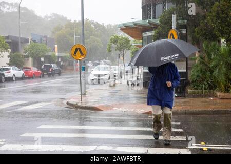 Sydney, Australia. 9 febbraio 2020. Forti piogge batter Sydney, la gente del posto lotta con gli ombrelli ad Avalon Beach Sydney in una giornata estiva umida e tempestosa, Australia Man su un passaggio pedonale combattendo con ombrello e piogge pesanti credito: martin Berry/Alamy Live News Foto Stock