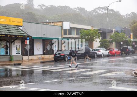 Forti tempeste e pesanti battitori di pioggia Sydney nel febbraio 2020, la gente del posto ad Avalon Beach Sydney che porta ombrelloni in una giornata di estati bagnate, Australia Foto Stock