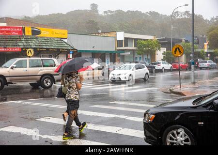 Forti tempeste e pesanti battitori di pioggia Sydney nel febbraio 2020, la gente del posto ad Avalon Beach Sydney che porta ombrelloni in una giornata di estati bagnate, Australia Foto Stock