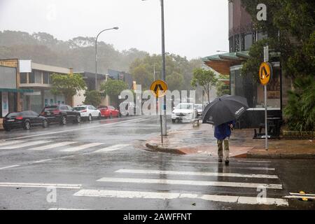 Forti tempeste e pesanti battitori di pioggia Sydney nel febbraio 2020, la gente del posto ad Avalon Beach Sydney che porta ombrelloni in una giornata di estati bagnate, Australia Foto Stock