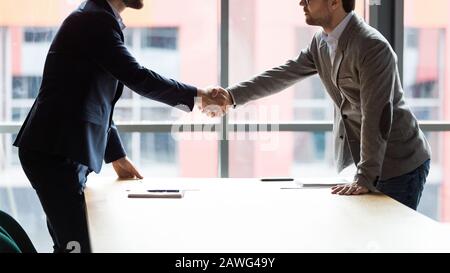 Due uomini d'affari scuotono le mani durante la riunione, prendendo un accordo Foto Stock