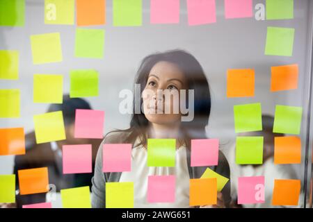 Serio asiatico businesswoman team leader leggendo le attività su carta appiccicosa Foto Stock