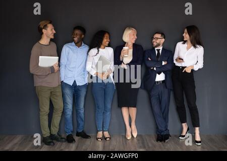 Diversi rappresentanti aziendali di successo in piedi appoggiati su sfondo nero muro Foto Stock