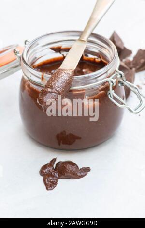 Cioccolato alla nocciola vegano fatto in casa spalmato su un coltello e in un recipiente da forno Foto Stock