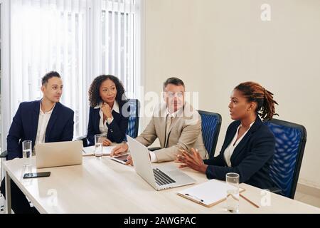 Team multietnico che si occupa di brainstorming al tavolo dei grandi uffici Foto Stock