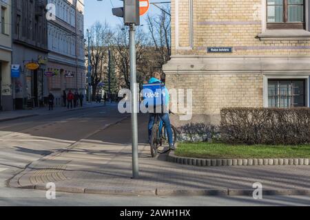 Città Riga, Lettonia. Consegna rapida di cibo in bicicletta. Un ciclista si trova sulla strada con una scatola di cibo. 07.02.2020 Foto Stock