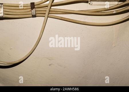 Vecchi fili elettrici o cavi appesi alla parete. Sfondo industriale Foto Stock