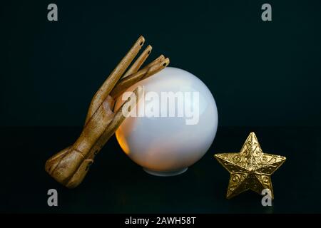 vita immobile esoterica creativa con una sfera di previsioni e due mani femminili di legno su uno sfondo nero Foto Stock