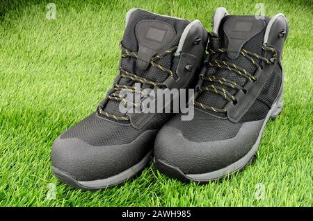 Coppia di nuovi stivali di protezione per la sicurezza sul lavoro su fondo erboso artificiale Foto Stock