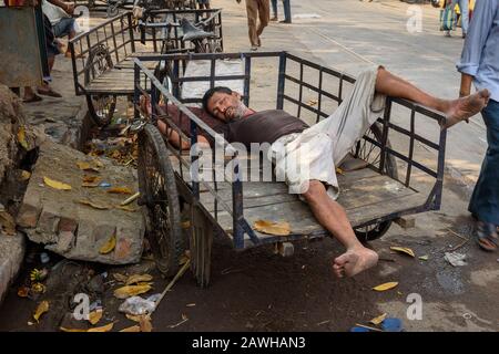 L'uomo indiano dormiva sul suo rickshaw cargo in bicicletta sulla strada a Kolkata. India Foto Stock