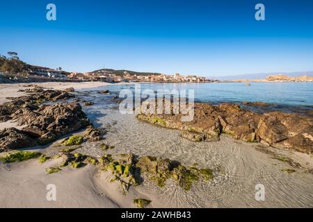 Rocce lungo la spiaggia e un tranquillo mare mediterraneo a l'Ile Rousse nella regione Balagne della Corsica in una giornata di sole brillante Foto Stock