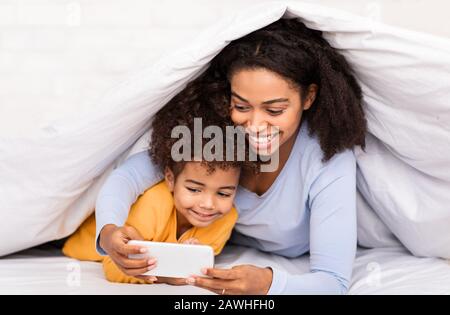 Madre E Figlia Che Utilizzano Lo Smartphone A Casa Foto Stock