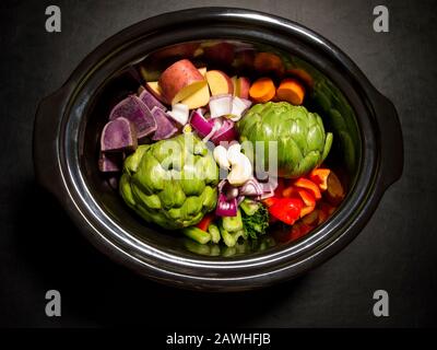 Grande pentola nera con verdure tritate su di essa pronta a cucinare. Cucina lenta, pentola di raccolto. Concetto sano. Foto Stock