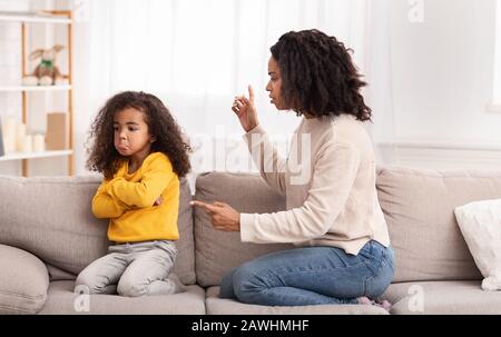 Madre Nera Scolding Figlia Seduto Sul Divano A Casa Foto Stock