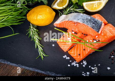 Filetto di salmone affettato su tre parti con lime, sale, pepe, rucoli, finocchio e rosmarino, pronto per cucinare. Foto Stock