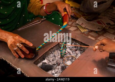 India, Rajasthan, Shekhawati, Nawalgarh, che fanno i tradizionali angoli lac a mano, torcendo per formare il modello a spirale, oro e blu bangle di colore Foto Stock