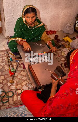 India, Rajasthan, Shekhawati, Nawalgarh, madre e figlia che fanno i bangles tradizionali del lac a mano, fondendosi per ammorbidire il materiale sopra il fuoco di carbone Foto Stock