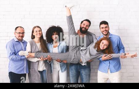 Gioiosi Colleghi Multietnici Che Si Divertiscono, Posando Sopra White Brick Wall Background Foto Stock