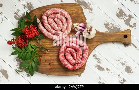 Spagnolo longaniza es un embutido largo originario de España, salsicce di manzo crudo fatte in casa con pepe rosa sul tagliere Foto Stock