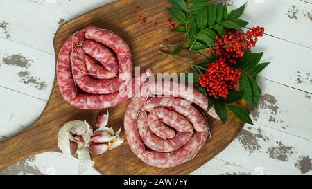 Spagnolo longaniza es un embutido largo originario de España, salsicce di manzo crudo fatte in casa con pepe rosa sul tagliere Foto Stock