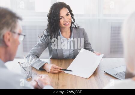 Indietro biew di coppia matura che firma il contratto all'ufficio Foto Stock