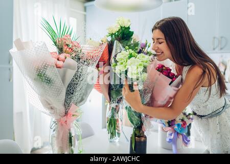 San Valentino, giorno donne. Donna ha trovato molti bouquet di fiori in cucina. Ragazza felice che smelling rose Foto Stock