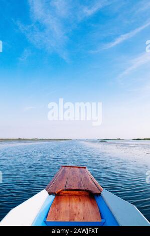 Thai barca dalla coda lunga centina anteriore in pacifica di Nong Harn lago, Udonthani - Thailandia. La barca di legno sotto il bel blu cielo mattutino su rosso lotus lake. Foto Stock